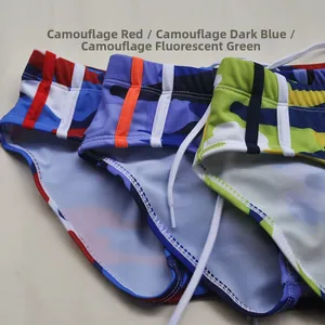 Flat lay of camo swim trunks in red, navy, and lime with drawstrings and side stripes