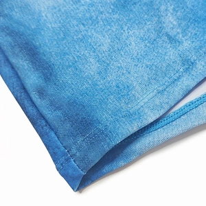 Detailed close-up showing the blue denim print pattern and stitched hem of men's swim trunks