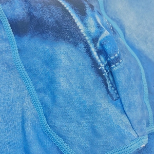 Macro shot of faux denim print fabric with visible stitching for men's swim trunks