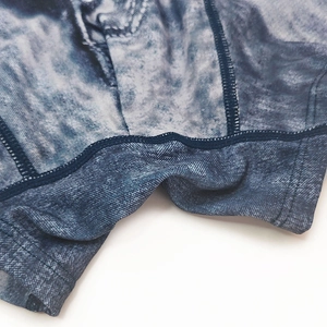 Detailed close-up of denim print men's swim trunks featuring reinforced blue topstitching