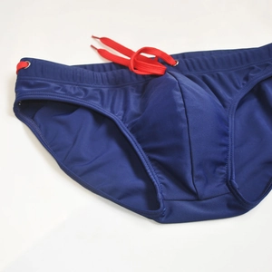 Detail of navy blue men swim briefs with red drawstring and metal eyelet accents