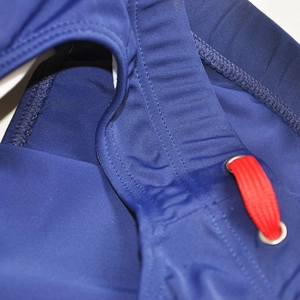 Detail of navy blue swim briefs showing red drawstring, metal eyelets and reinforced stitching