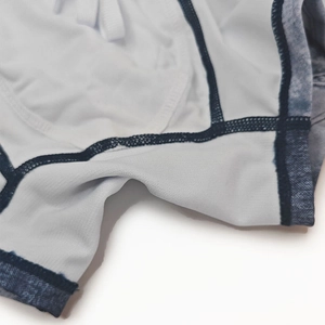 Close-up of white swim trunks featuring denim print trim and blue reinforced stitching details
