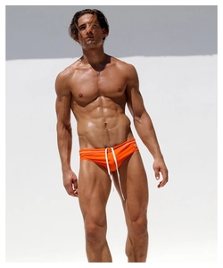 Front view of low-rise bright orange men's swim briefs with white drawstring on a model