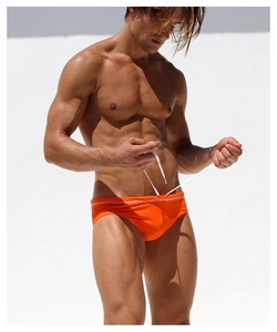 Detail of bright orange men's swim briefs with white adjustable drawstring and elastic fabric
