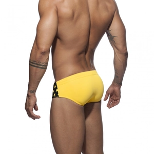 Rear view of bright yellow men's swim briefs featuring black star print side panels