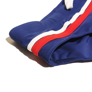 Detailed macro view of navy blue swimwear fabric with red and white side stripes