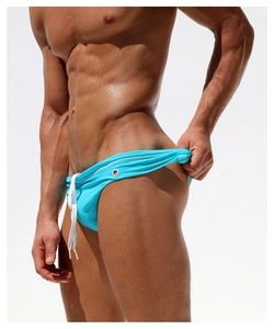 Detail of bright blue men's swim briefs featuring white drawstring and silver metal eyelets