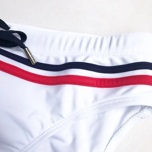 Detail of men's white swim briefs showing elastic waist with luxury metal cord tips