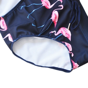 Close-up of men's navy blue swim trunks with pink flamingo print and drawstring detail