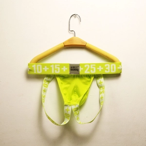 Detail view of neon green men's jockstrap with elastic waistband on wooden hanger