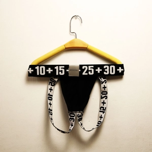 Detail of men's black cotton jockstrap with contrast logo waistband on a hanger