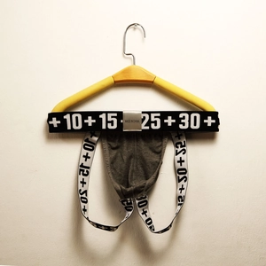 Detail of grey cotton jockstrap with graphic elastic waistband on a wooden hanger