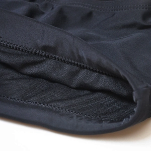 Detailed close-up of fine stitching and elastic lining on men's black swim trunks