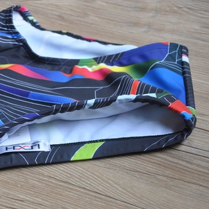 Macro detail of men's colorful geometric swim trunks showing quality stitching and brand tag