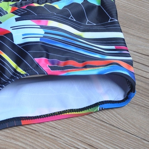 Close-up of double-stitched hem and white lining on colorful geometric men's swim trunks