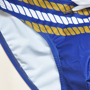 Detail of blue men's swim trunks with rope print, white drawstring and metal tips