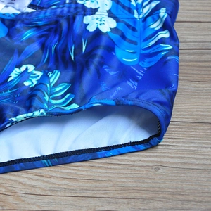 Detail of men's swim trunks with tropical leaf print and durable stitching finish