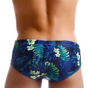 Men's swim trunks featuring tropical green leaf and white flower print on a navy base