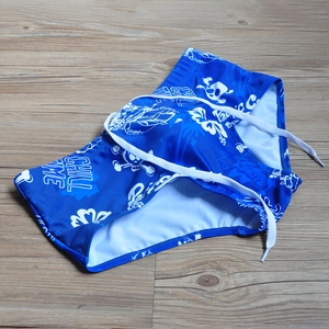 Detailed close-up of blue men's swim trunks featuring skull and floral graffiti patterns