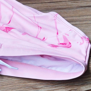 Dettaglio slip da nuoto uomo con stampa fenicottero e coulisse bianca su legno