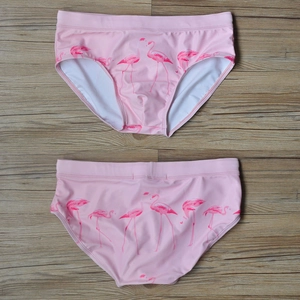 Detailed flat lay of pink flamingo print men swim trunks on a wooden background