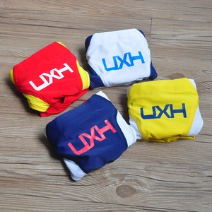 Flat lay of four colorful men's swim briefs in red, white, blue, and yellow with UXH logo