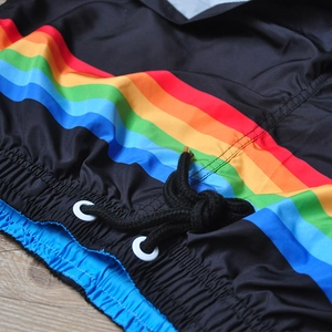 Dettaglio di strisce arcobaleno su pantaloncini sportivi neri con cordoncino e occhielli