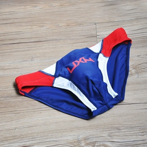 Flat lay of red, white and blue patchwork men's swim briefs with LDXN logo on wood background