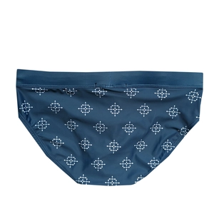 Detail of navy blue men's swim briefs with white geometric arrow prints and high-stretch fabric