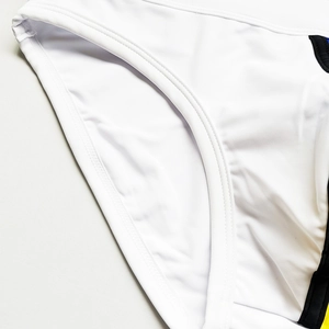 Close-up of white swimwear featuring black and red trim with durable flatlock stitching
