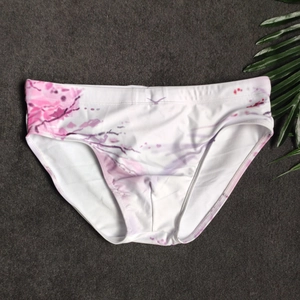 Close-up of men's floral swim briefs with pink ink print on white elastic fabric