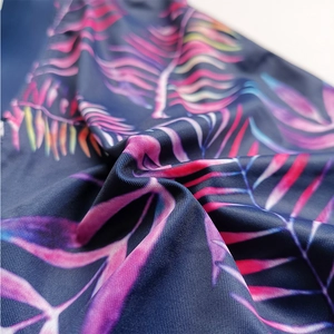 Detailed close-up of dark blue swimwear fabric featuring colorful tropical leaf prints