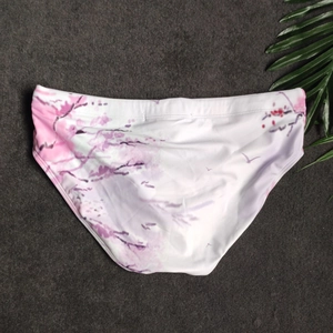 Flat lay detail of men's swim briefs with pink cherry blossom and bird print design