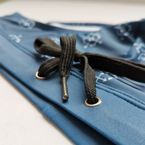 Detail of blue swim briefs with geometric print featuring elastic waist and black drawstrings