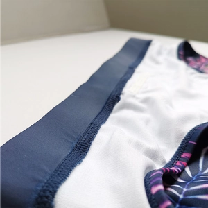 Detail view of tropical leaf print swim trunks with high-elastic blue waistband and lining