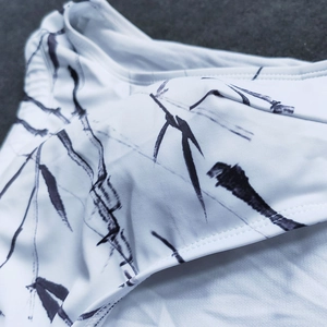Detail of white mens swim briefs with black ink bamboo leaf print and elastic texture