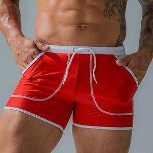 Detailed close-up of men's red swim trunks with side pockets and white drawstring waist