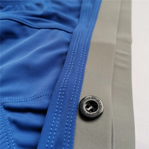 Macro detail of men's swim briefs showing grey elastic waistband and Super Body button