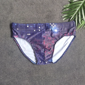 Detailed flat lay of purple pixelated mosaic print men swimming briefs on grey texture