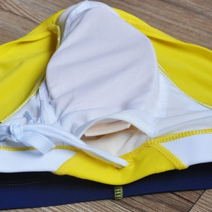 Close-up of swim briefs showing yellow fabric with white mesh lining and pad pocket