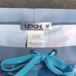 Dettaglio slip da nuoto blu floreale con etichetta UXH, coulisse e tag della taglia M