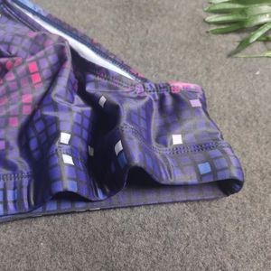 Detailed close-up of pixel mosaic printed swim trunks with purple and blue geometric patterns