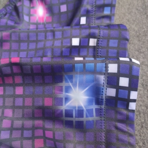 Detail of purple pixelated mosaic print on high-elasticity fabric with overlock stitching