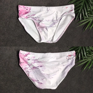 Detail view of mens floral swim briefs with pink cherry blossom prints on white fabric