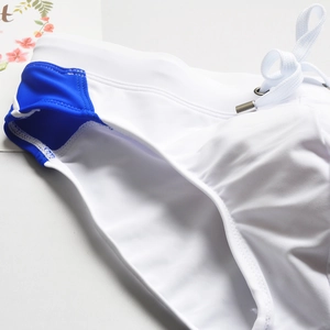 Gros plan détaillé du slip de bain homme blanc et bleu avec cordon et poche avant