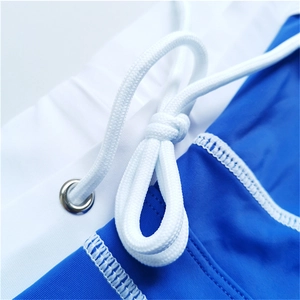 Detail of blue and white quick-dry swim trunks featuring white drawstring and metal eyelets