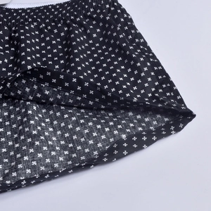 Close-up of men's cotton shorts showing black fabric with white clover print and elastic waist