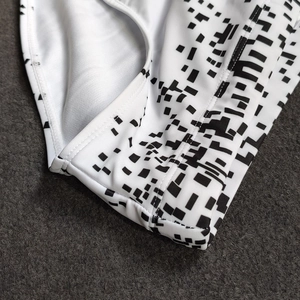 Close-up of geometric pixel print on elastic swimwear fabric with precision stitching