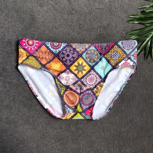 Detailed flat lay of men's swim briefs featuring colorful mandala patterns on grey background